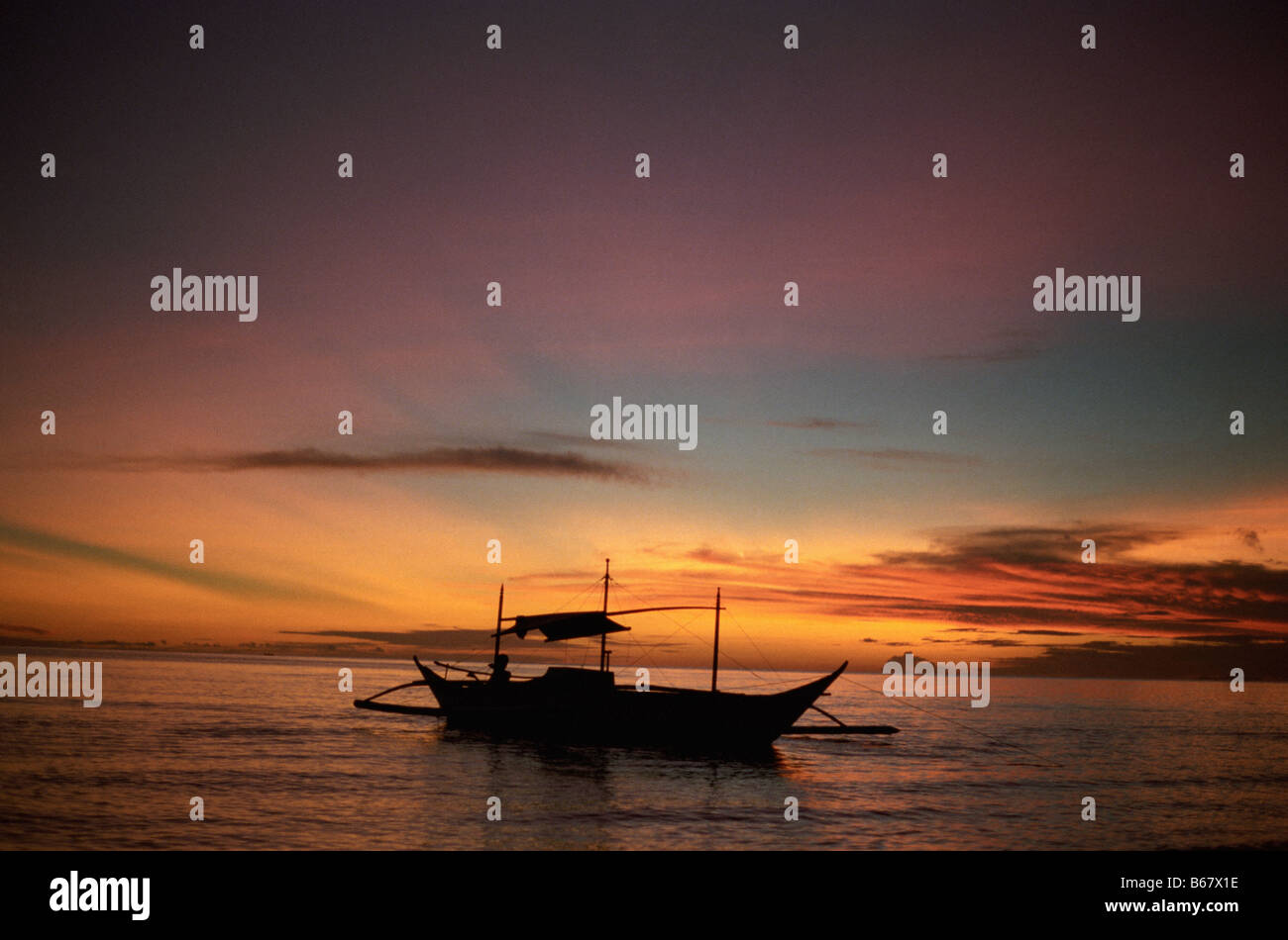 A colorful sunset and a silhouette of a fishing boat on Boracay Island, the Philippines Stock Photo