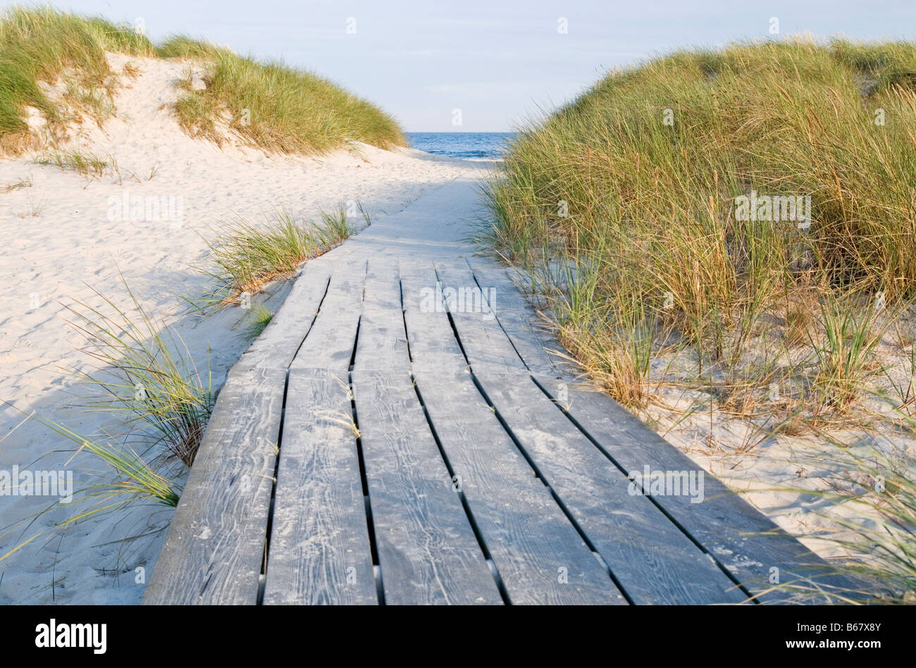 footbridge of wood leading down to the sea and sand beach Stock Photo