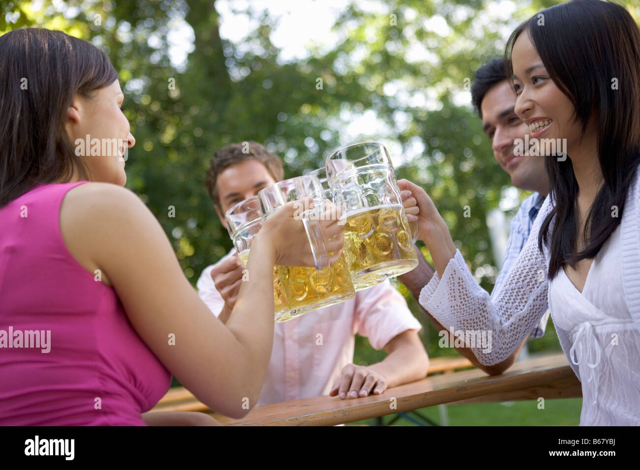 Four friends in a beer garden clinking glasses, Lake Starnberg, Bavaria, Germany Stock Photo