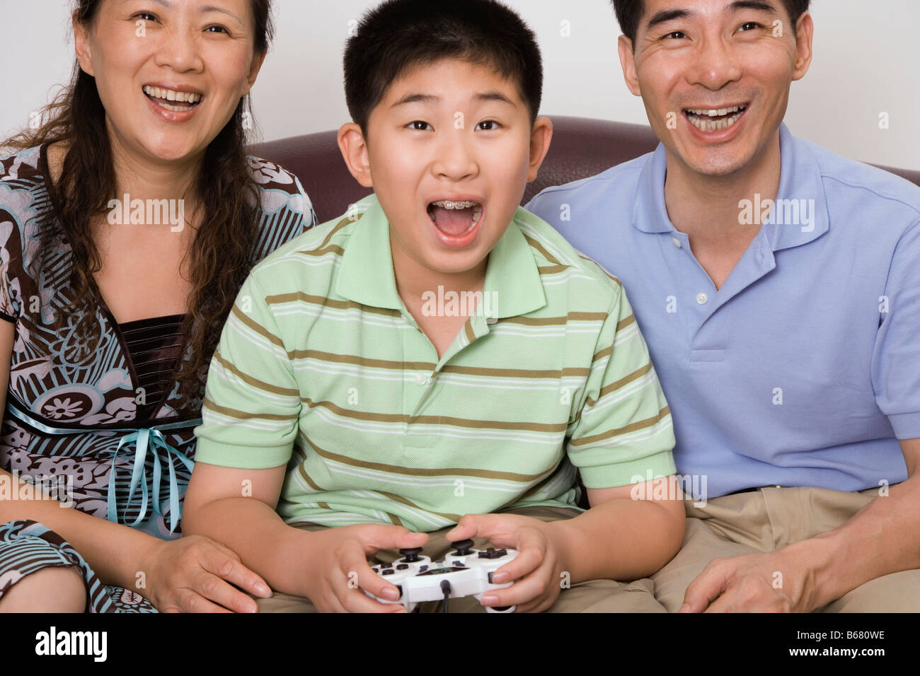 Mature couple sitting with their son playing video game Stock Photo