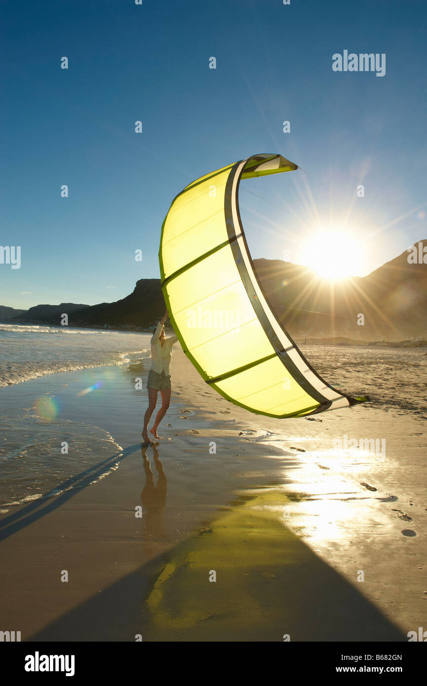 Woman holding kitesurfing sail on beach. Stock Photo