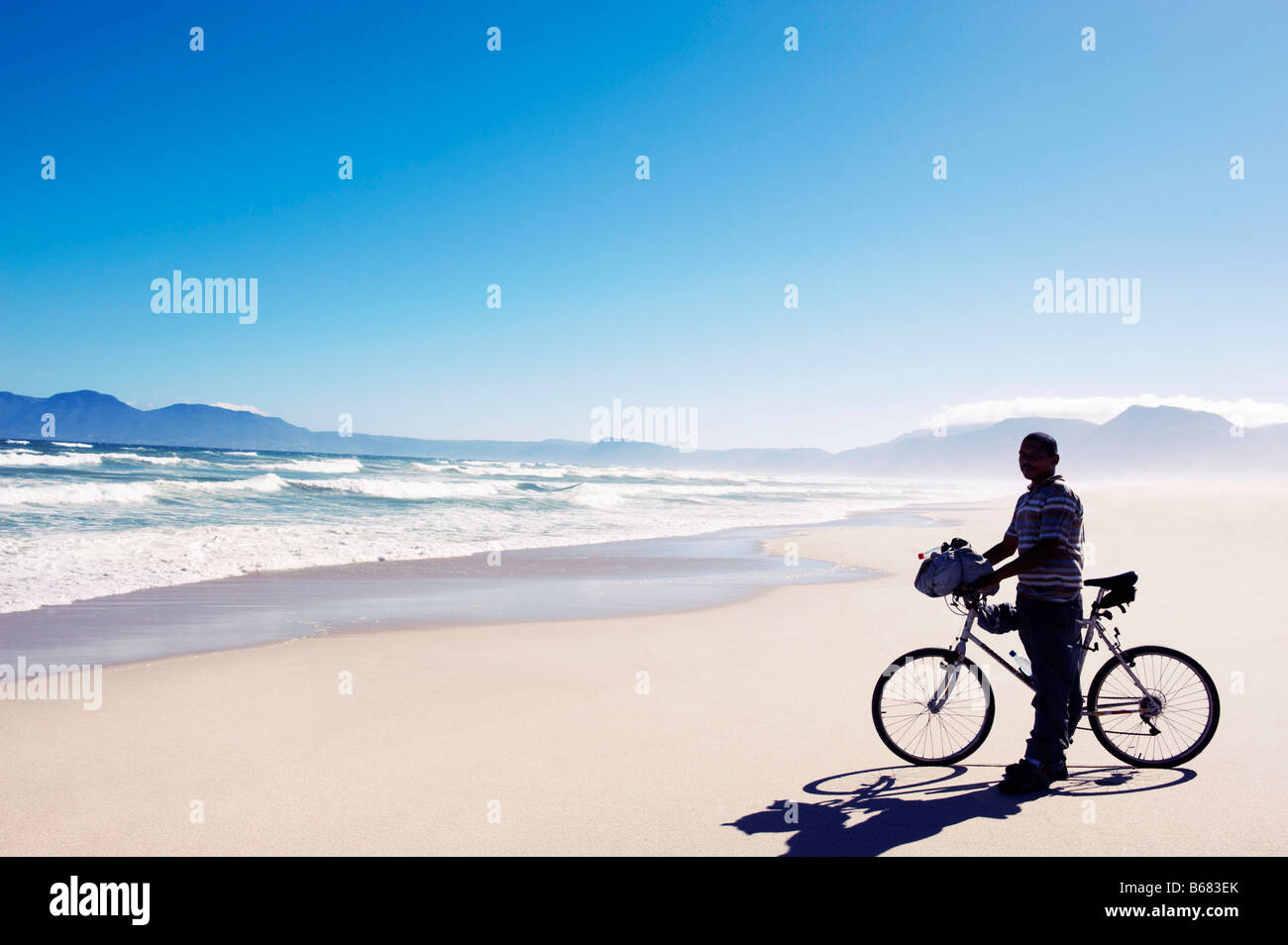 Black man with bike standing on beach Stock Photo
