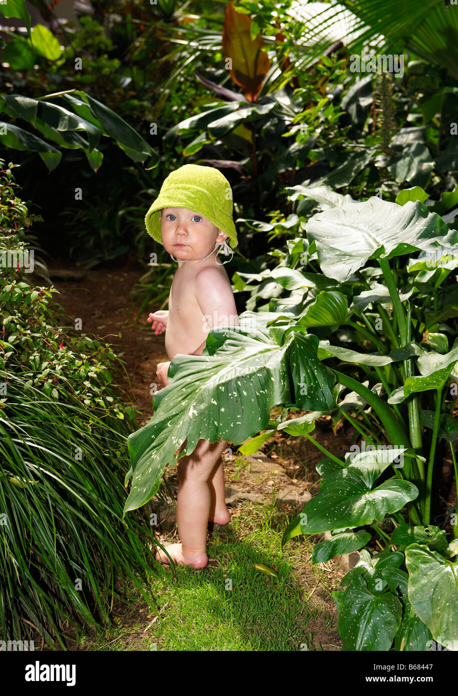 Little boy standing in jungle of plants Stock Photo