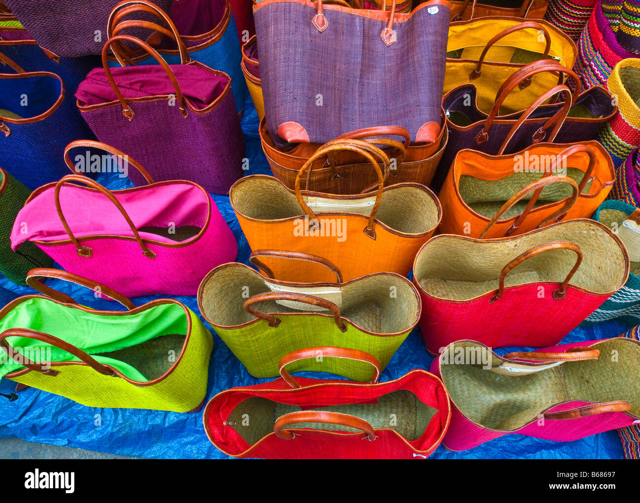 brightly coloured shopping bags on display at a marker stall in Sarlat France Stock Photo