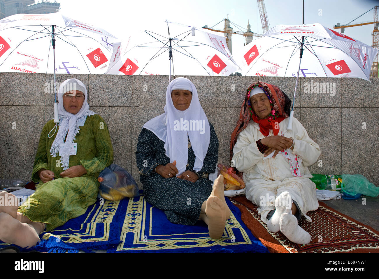 Three elderly tunisian ladies sitting on their prayer rugs just outside