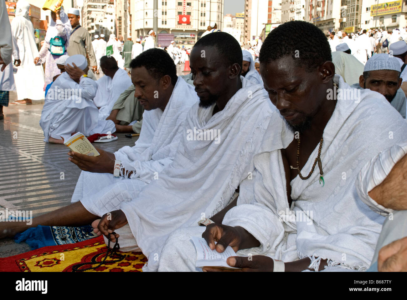 Three pilgrims sitting on their prayer rugs while they are offering