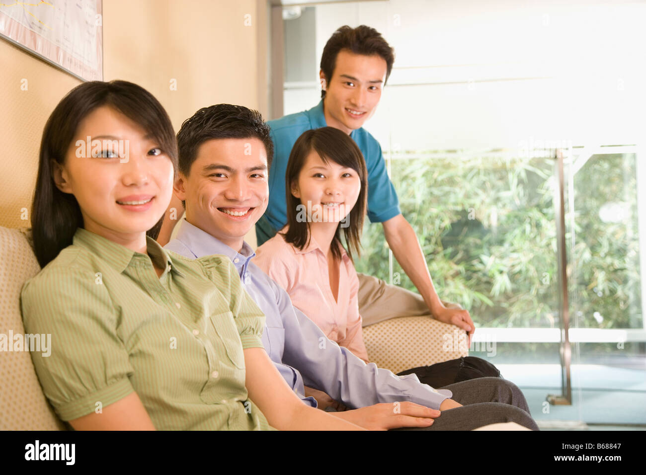 Portrait Of Two Young Men And Two Young Women Sitting On A Couch And ...