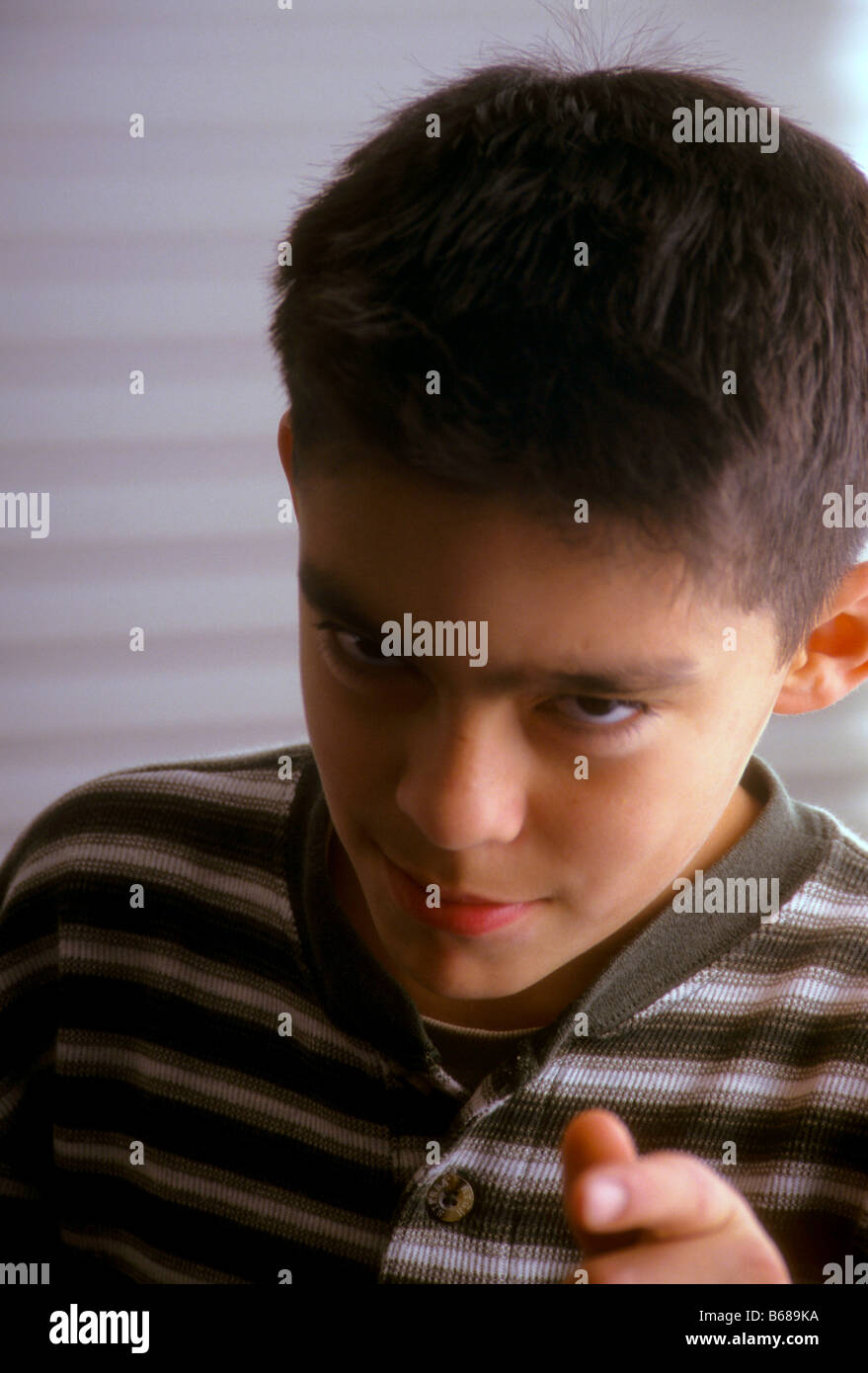 Hispanic boy gives coy look and points at camera. Stock Photo