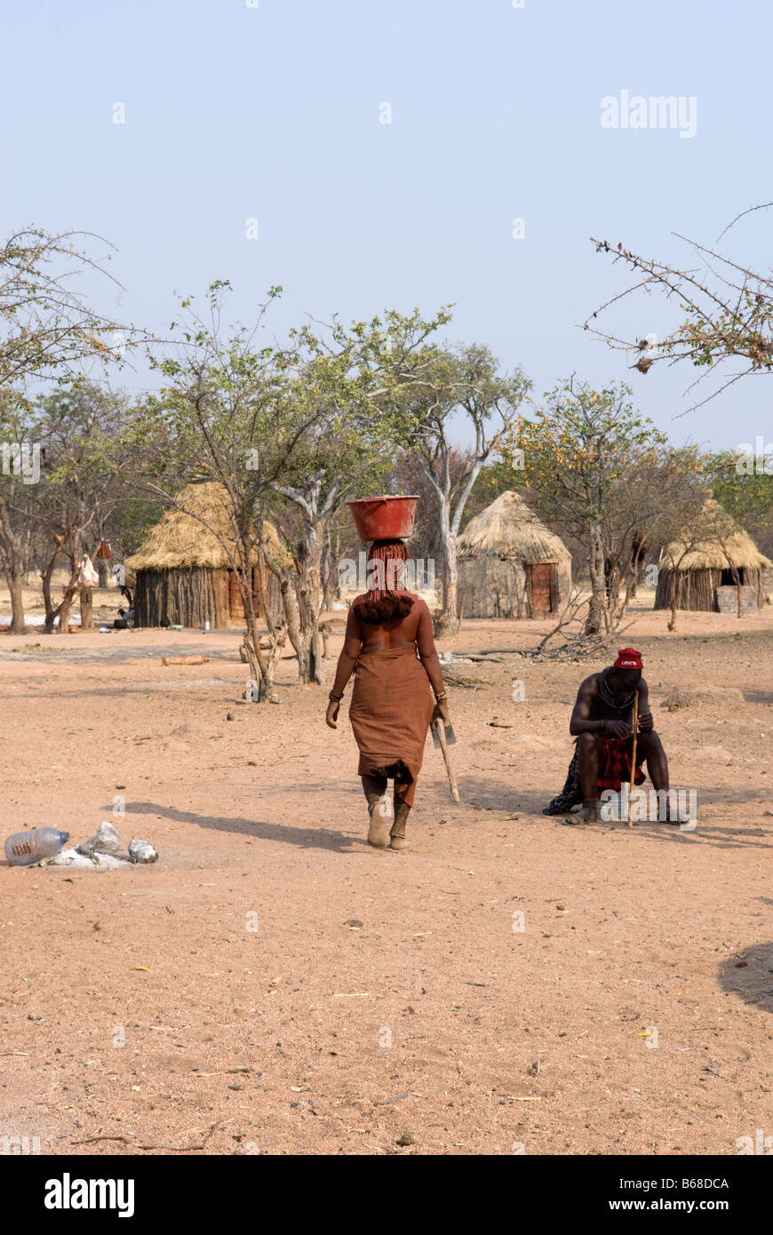 A tribeswomen carrying a panier on her head at the traditional Himba Oase Village near Kamanjab Namibia Stock Photo