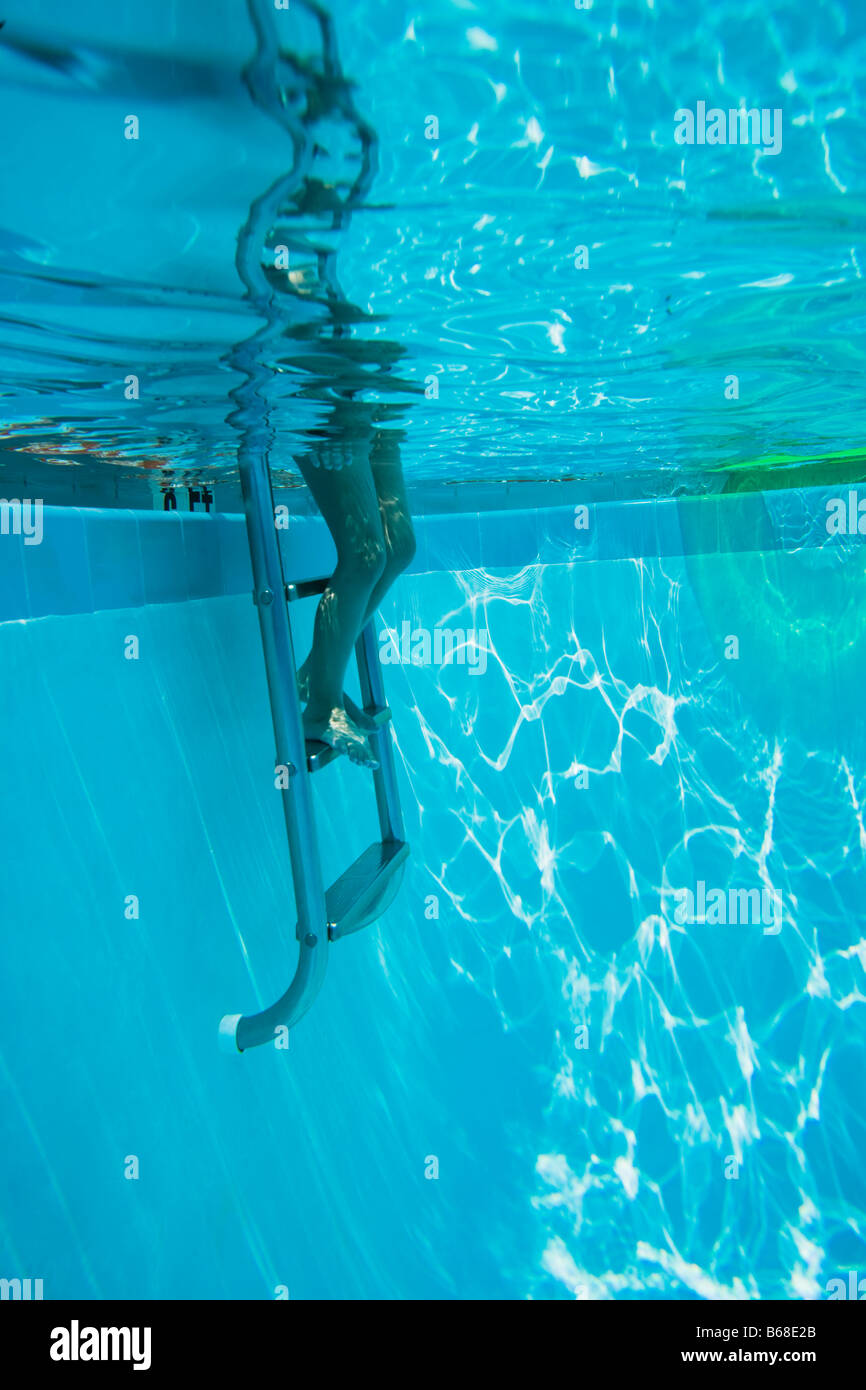 Legs on step ladder in swimming pool Stock Photo