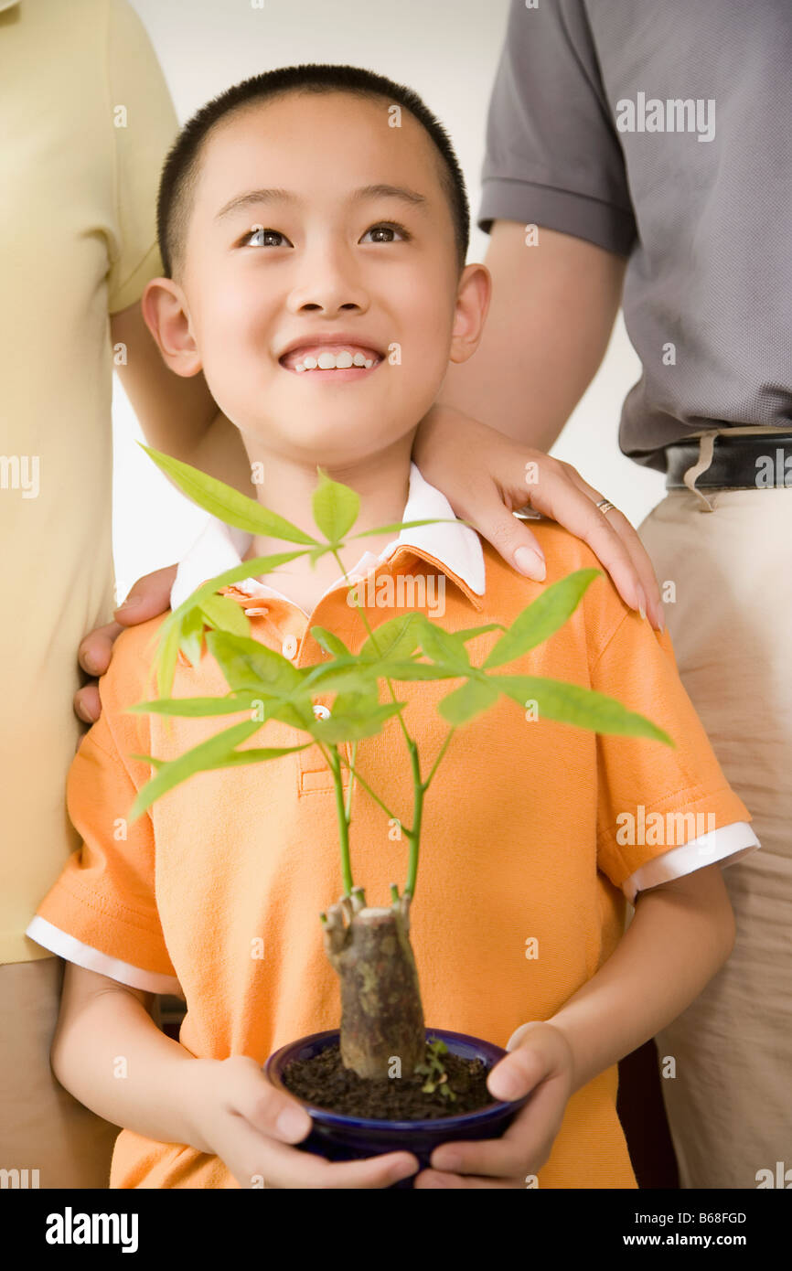 Boy standing and holding a potted plant Stock Photo - Alamy