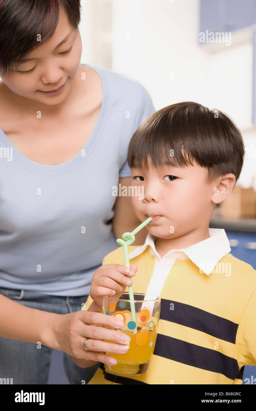 Boy drinking juice from a glass held by his mother Stock Photo Alamy