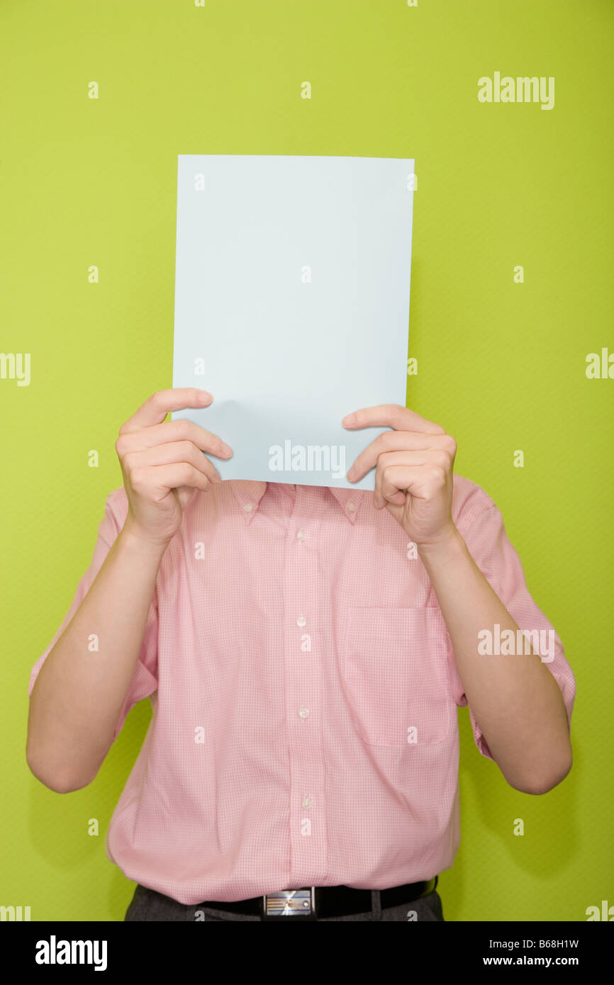 Male office worker hiding his face with a paper Stock Photo