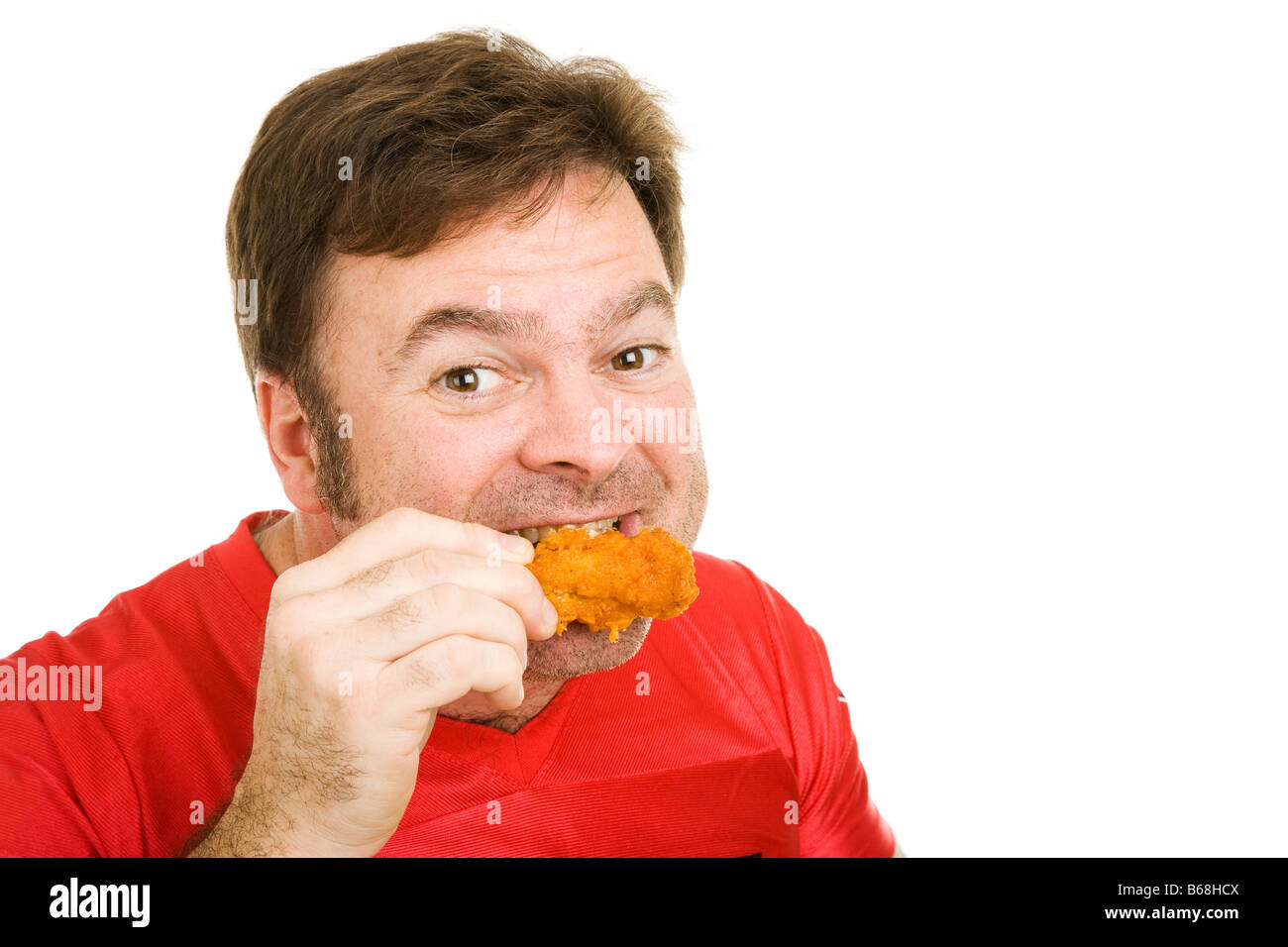 Middle aged man in football jersey enjoying a tasty fried buffalo wing Isolated on white Stock Photo