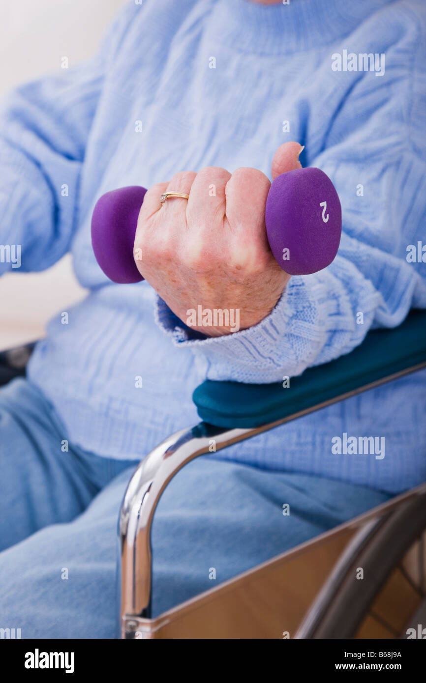 Senior woman exercising with hand weights, close-up of hand Stock Photo
