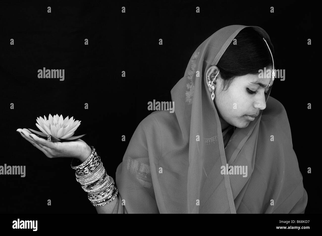 Indian woman offering a Nymphaea Tropical waterlily flower in a sari. Monochrome Stock Photo