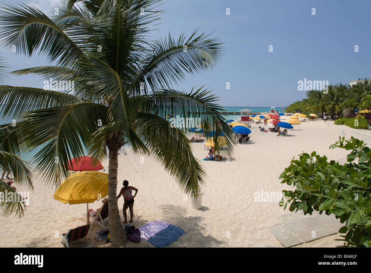 Jamaica Montego Bay Tourists and palm tree along white sand beach at Doctor s Cave Stock Photo