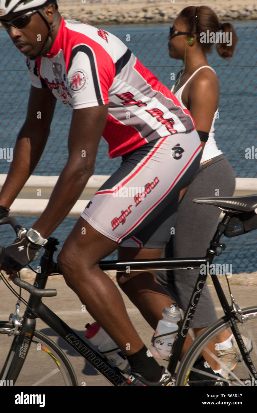 Black cyclist in red white jersey riding by Stock Photo