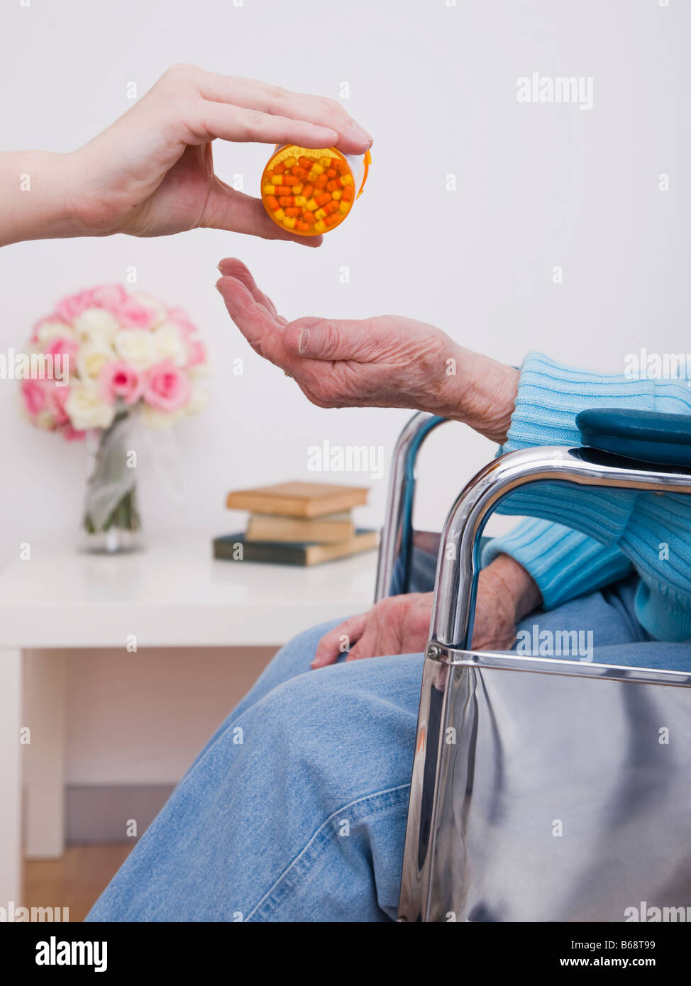 Young woman giving pills to senior woman, close-up of hands Stock Photo