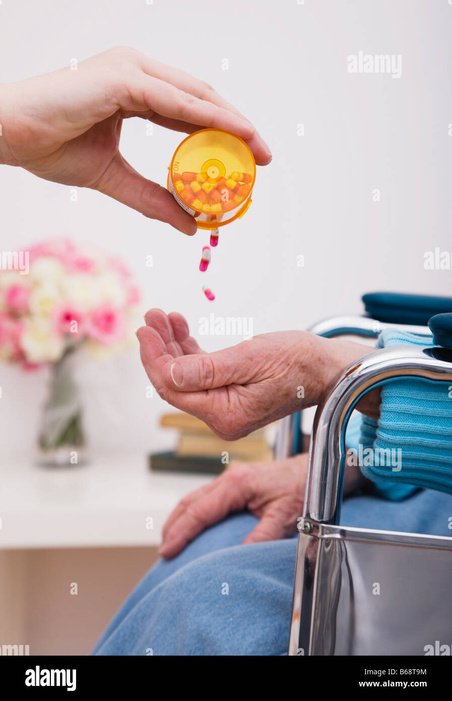 Young woman giving pills to senior woman, close-up of hands Stock Photo