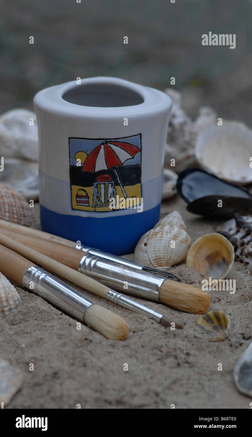 Paint brushes and shells on the beach Stock Photo