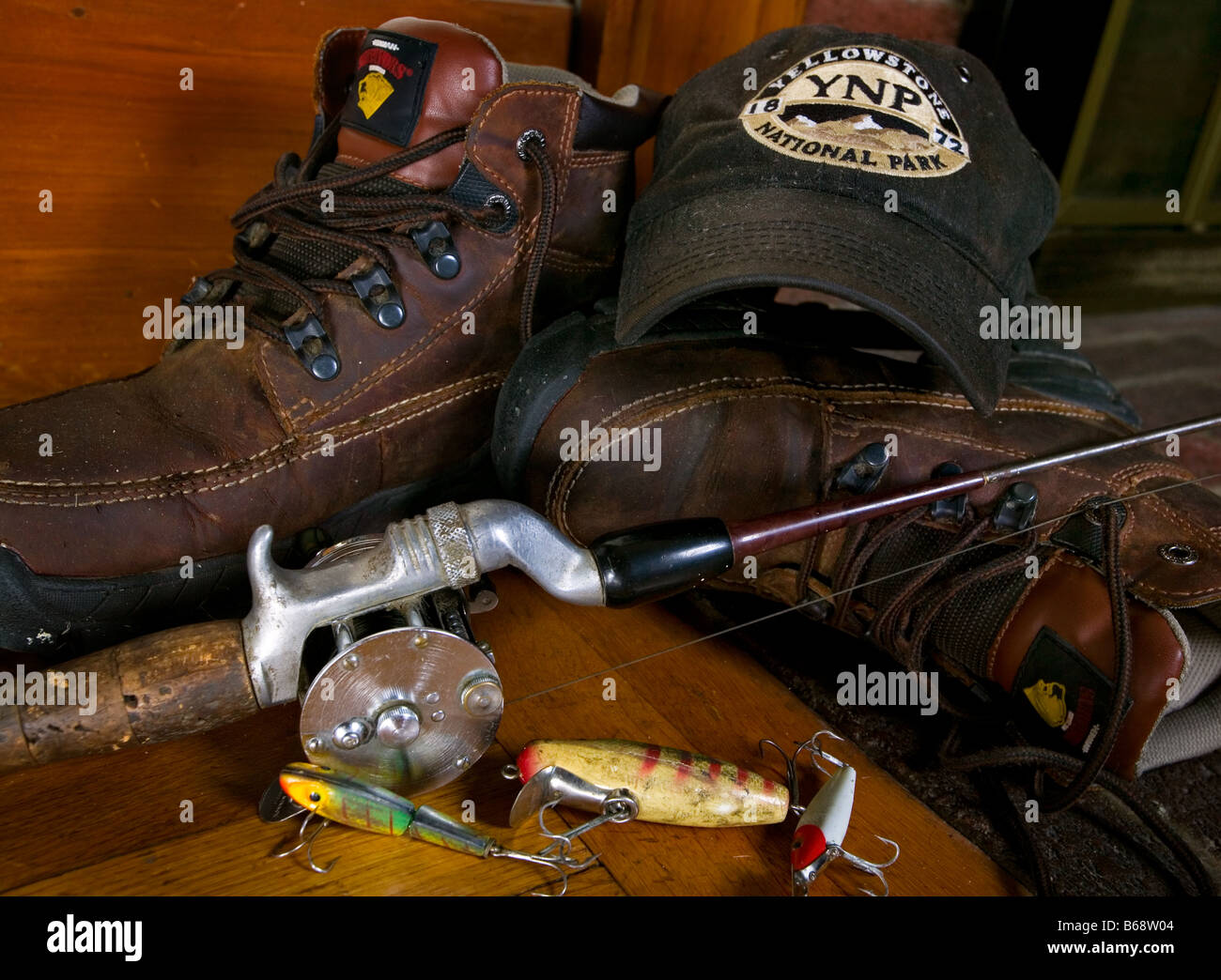 An old rod and reel with a fishing lure and worn hiking boots Stock