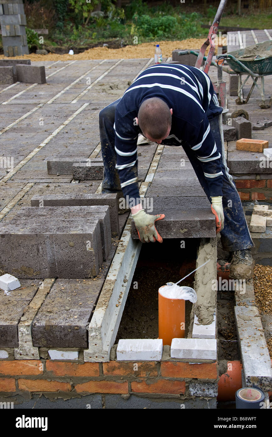 Workman laying concrete blocks to build the first stage of a house