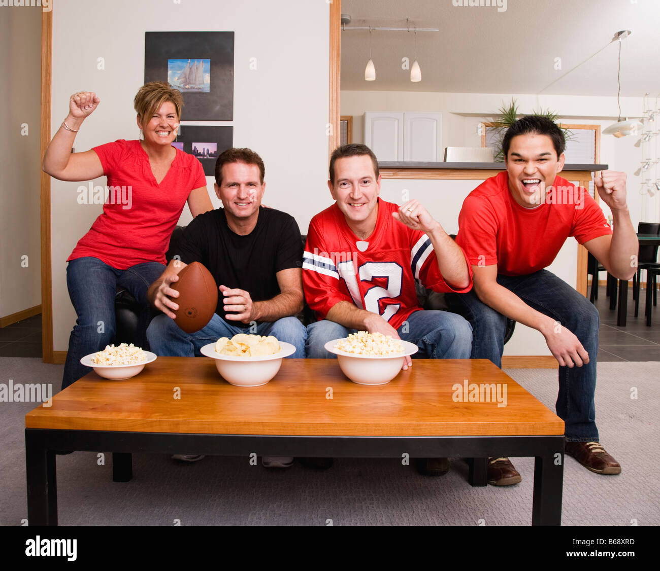 Four football fans cheering in living room Stock Photo