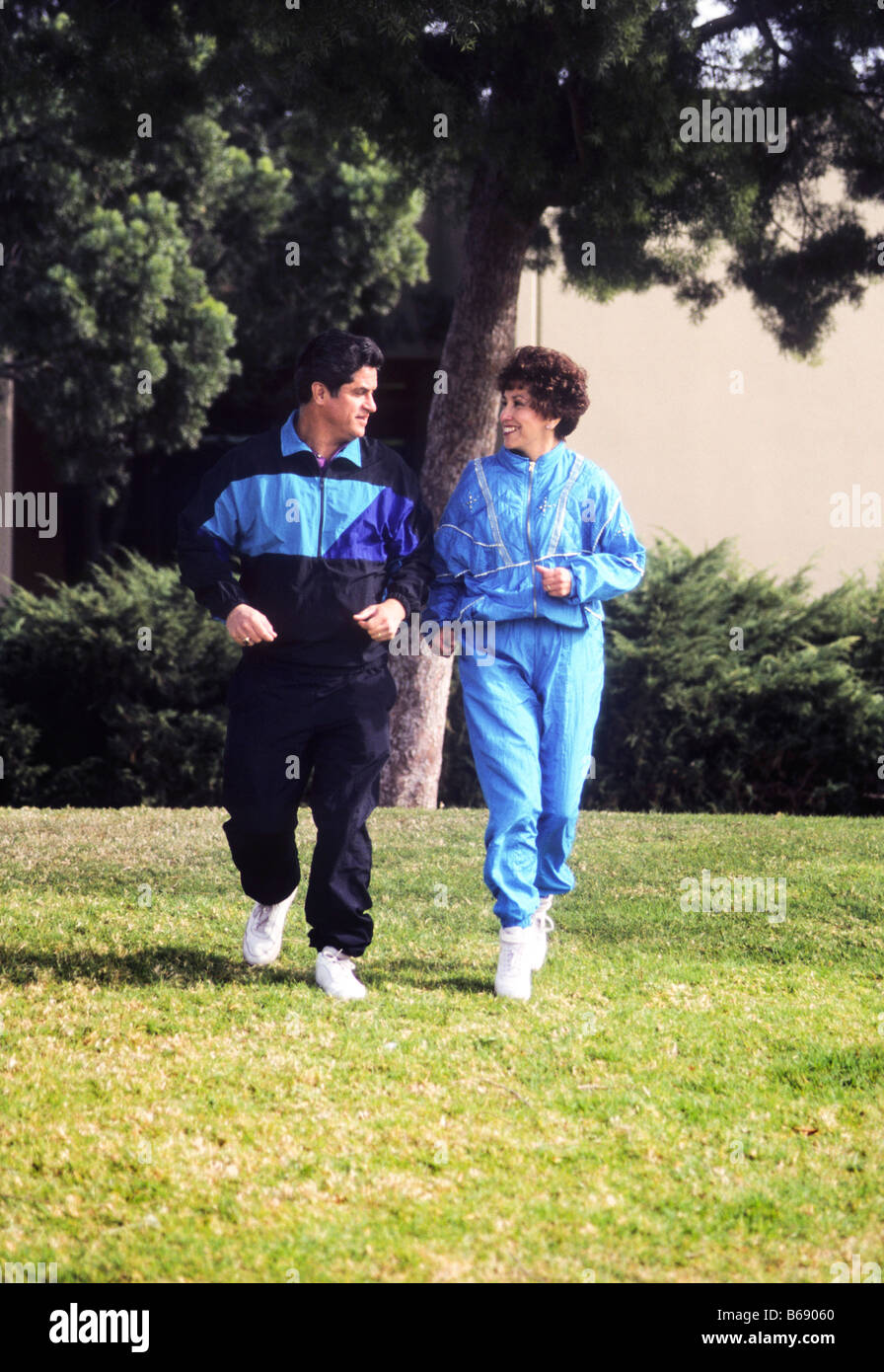 Hispanic couple in exercise clothing jog in park. Stock Photo