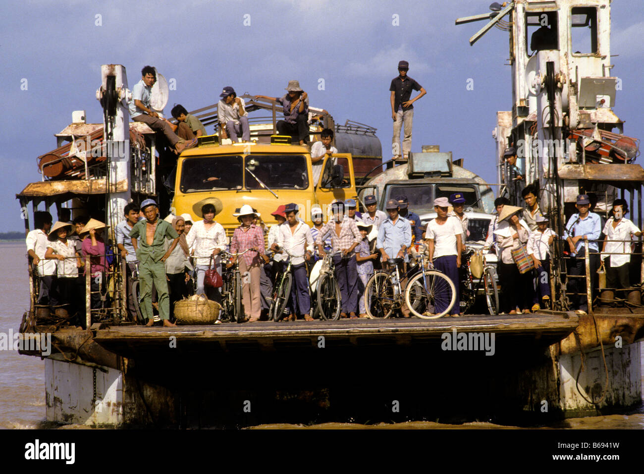 A ferry boat carrying vehicles and passengers crosses the Mekong River ...