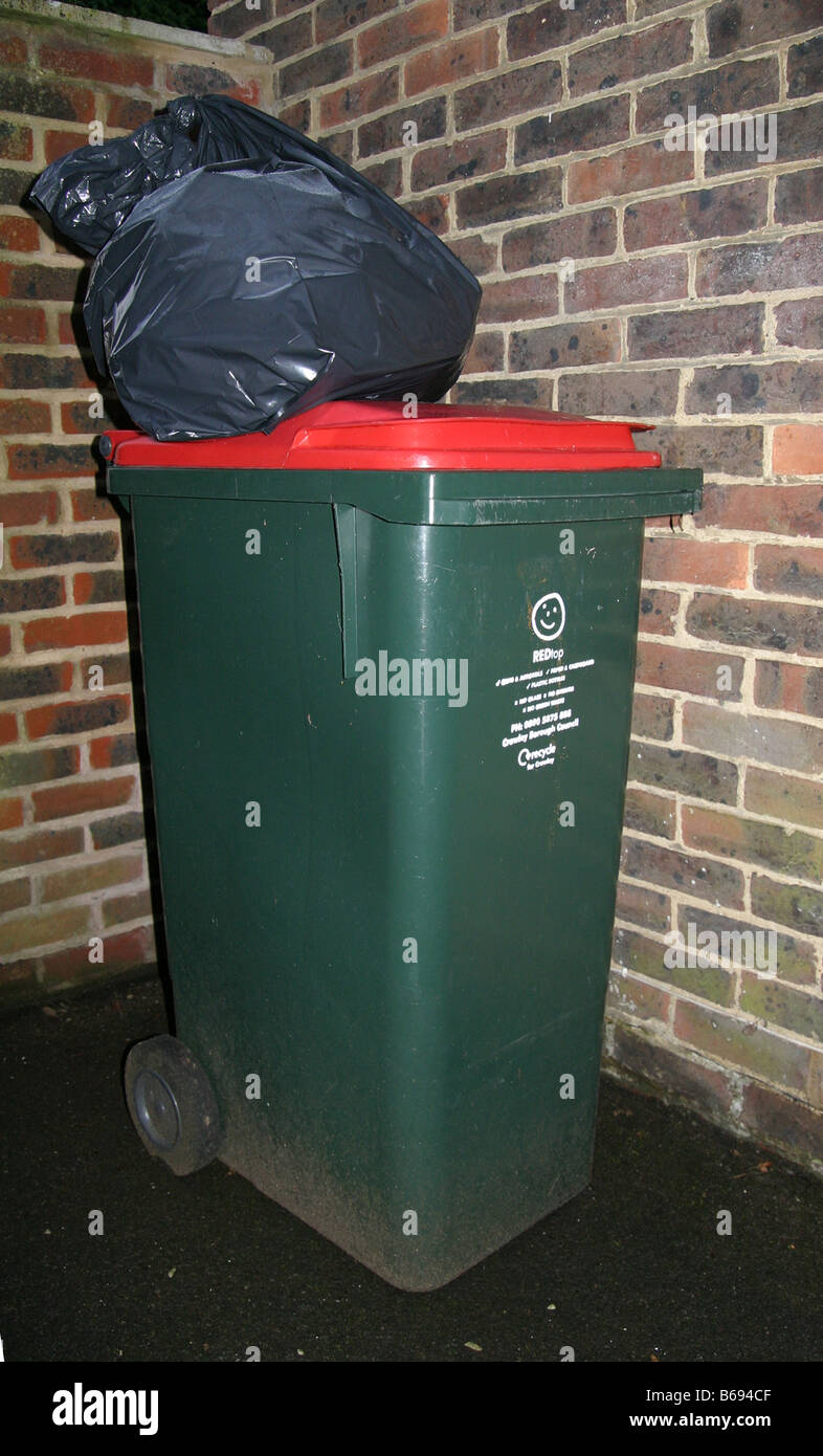 Red top green wheelie bin with bag of rubbish on top Stock Photo Alamy