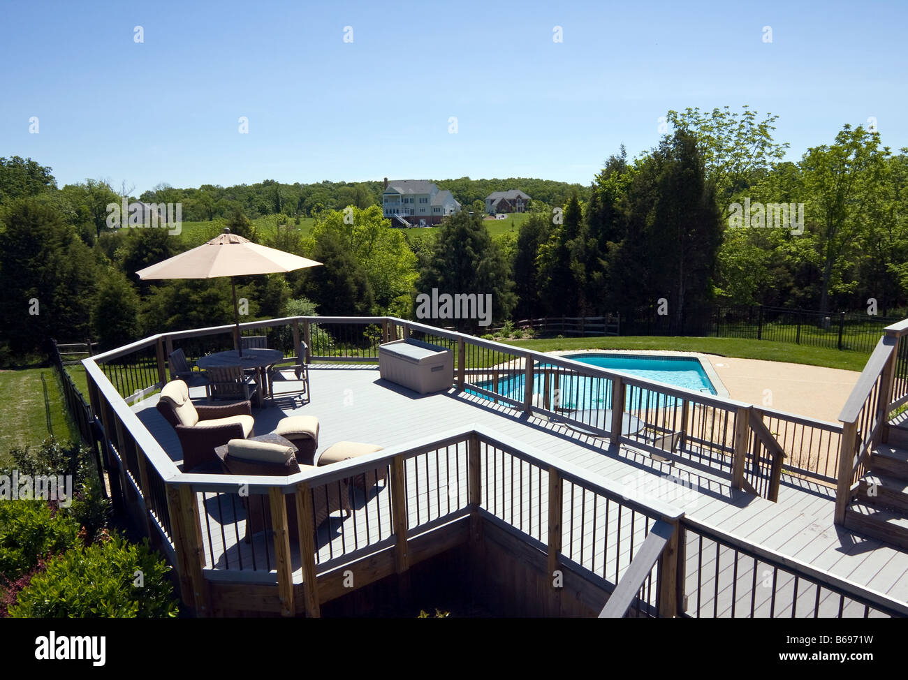 Modern wooden deck overlooking a swimming pool in modern suburban garden Stock Photo