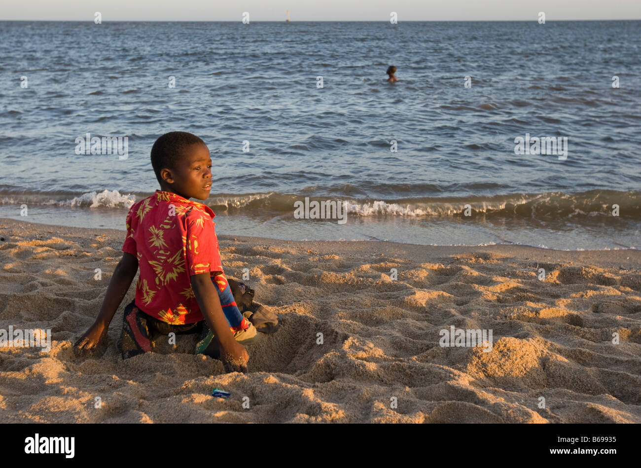 Africa Mozambique Maputo Portrait of young boy playing in sand along Indian Ocean on beach at sunset Stock Photo