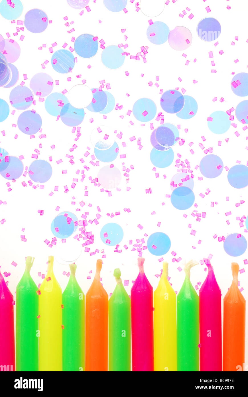 Row of unlit birthday candles with confetti and cake sprinkles Stock