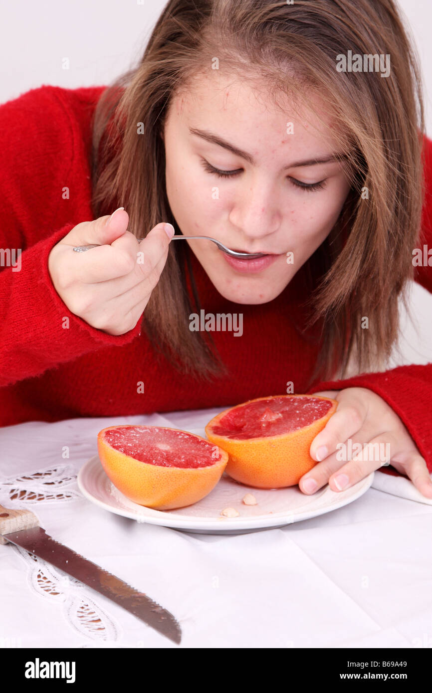 teen eating a grapefruit for breakfast Stock Photo Alamy