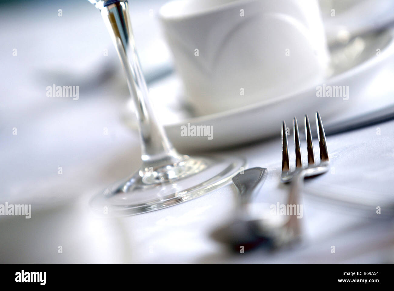 Place setting at a restaurant dinner table with fork spoon wine glass and cup Stock Photo