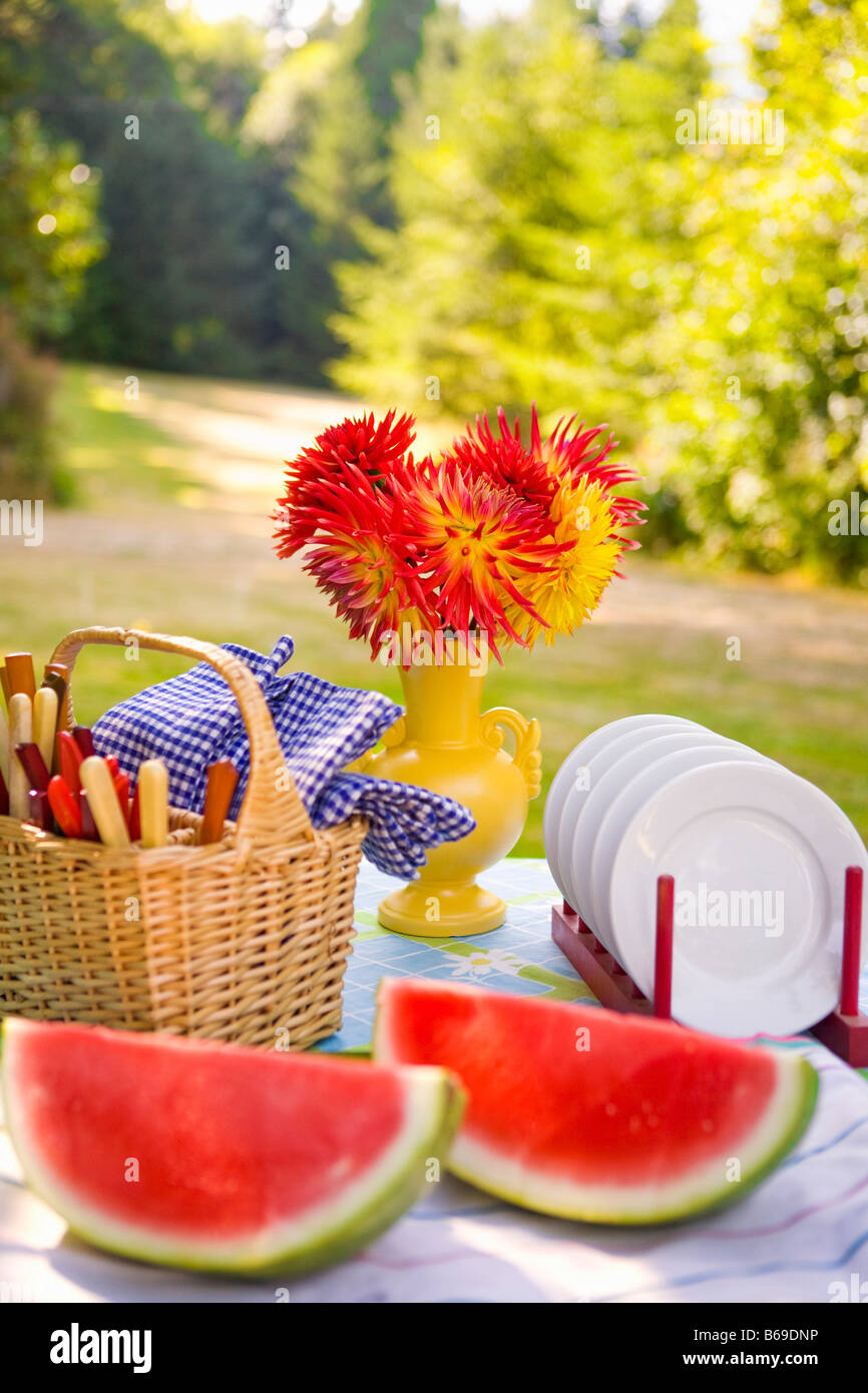 Two watermelon slices with a basket and a vase of flowers on a table Stock Photo