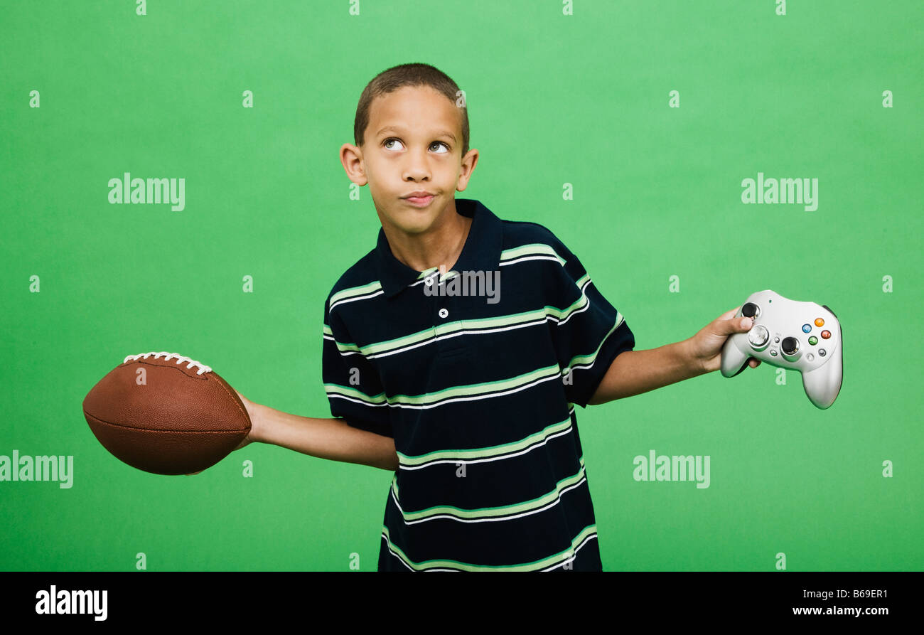 Boy (10-12) holding football and computer joy pad, studio shot Stock Photo