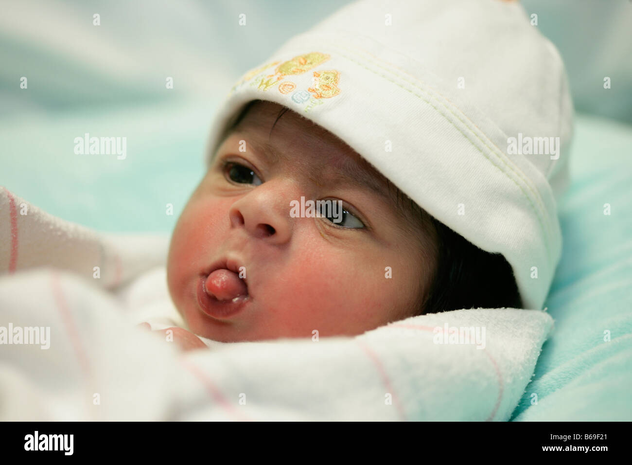 Two day old baby girl sticks her tongue out in a confident, playful gesture. Stock Photo