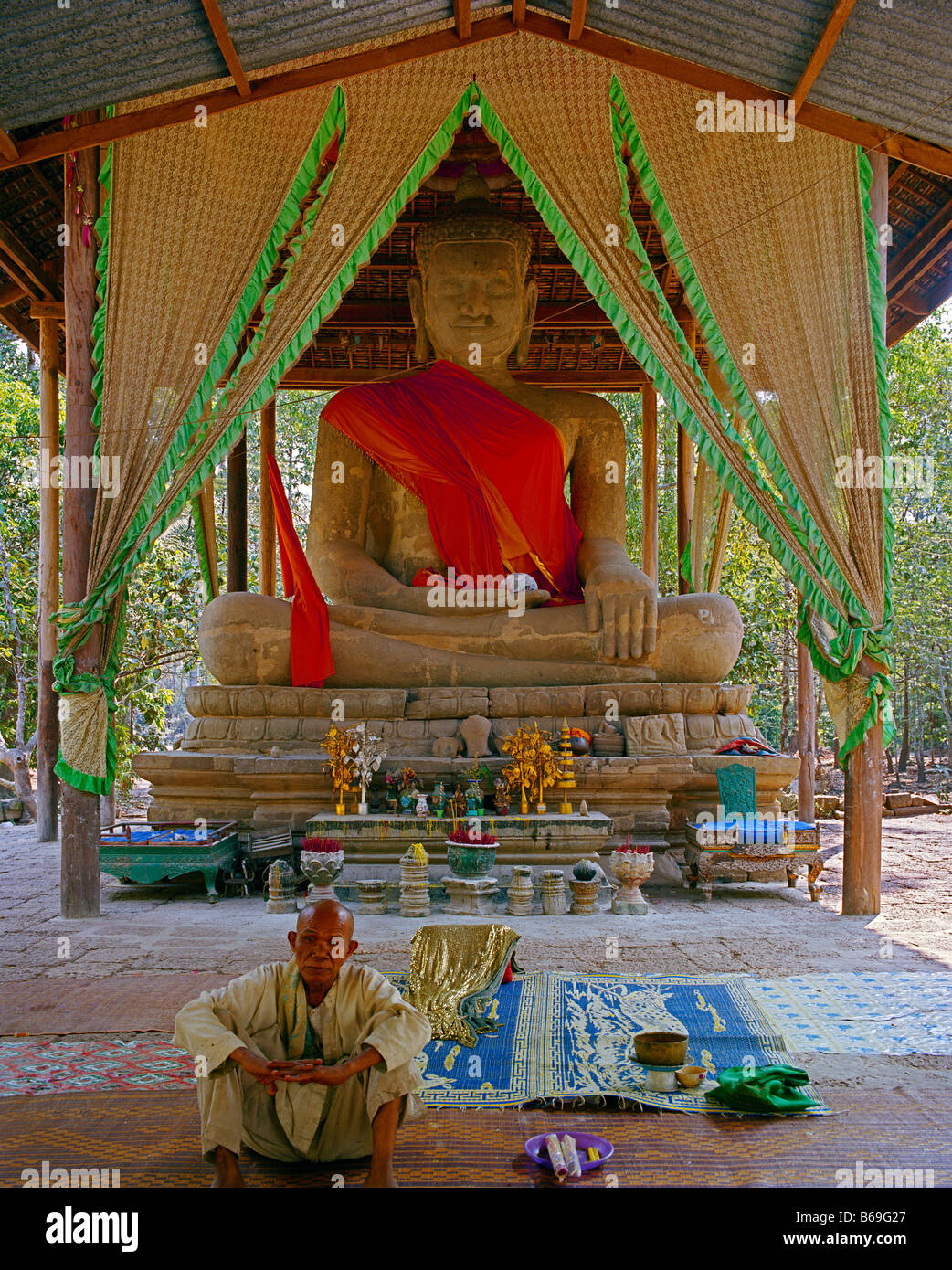 old monk in front of a roofed large buddha statue alter Mönch vor großer Buddhastatue Stock Photo