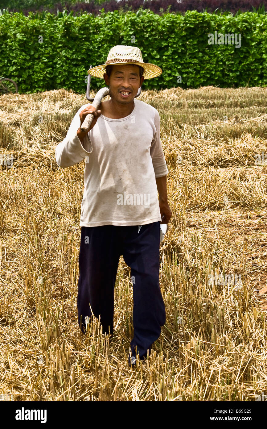 Mature man holding pitchfork in a field, Zhigou, Shandong Province