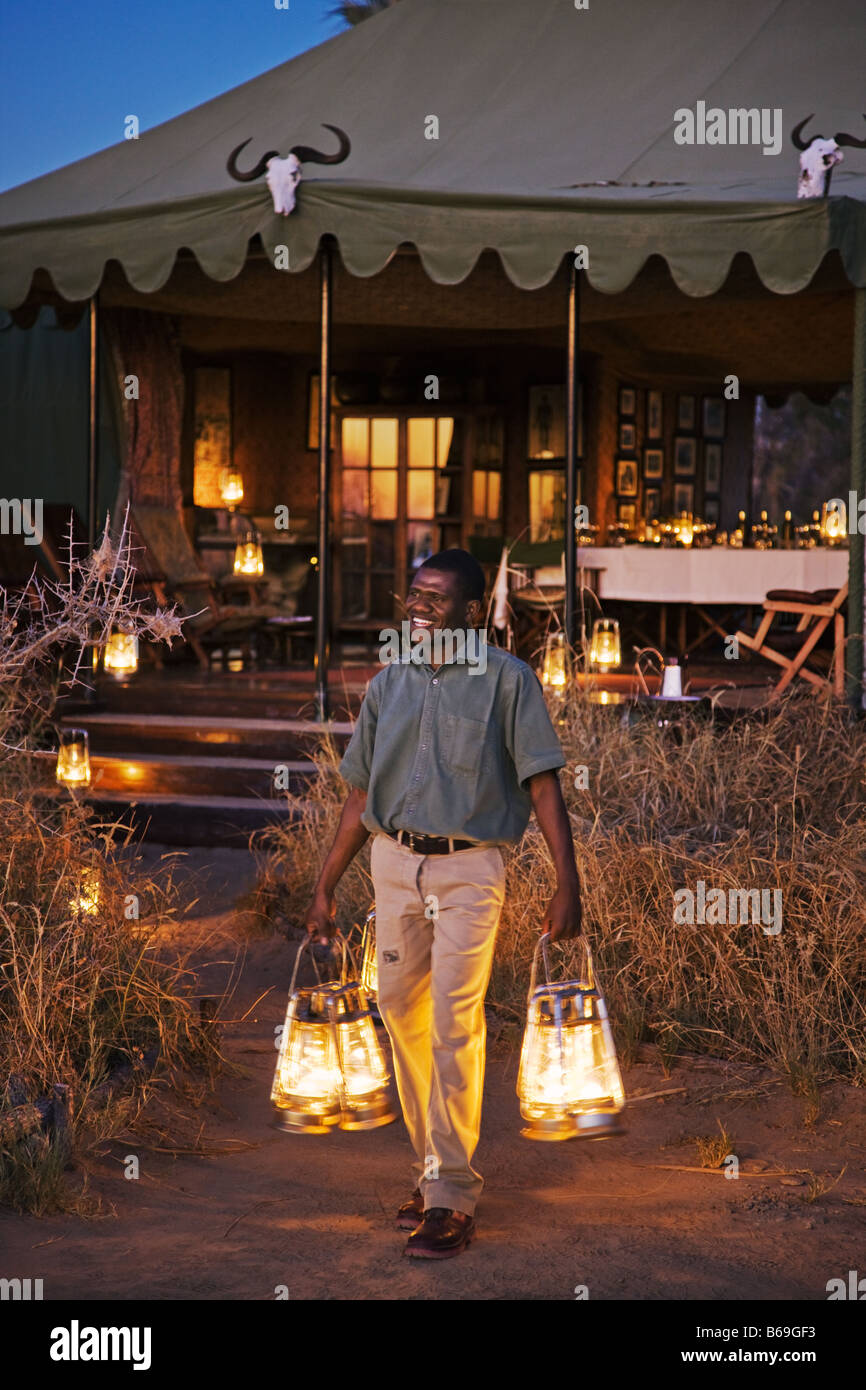 Staff member of Jack s camp putting out the evening parafin lanterns to light the path to the Mess tent Makadikadi Pan, Botswana Stock Photo