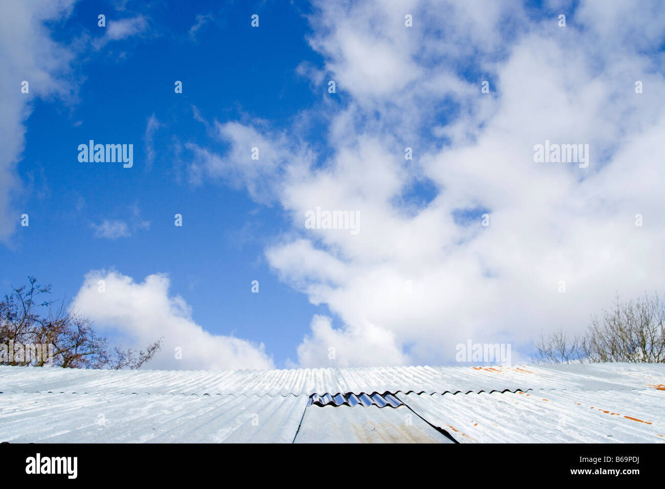 corrugated roof with blue sky and fluffy white clouds Stock Photo - Alamy