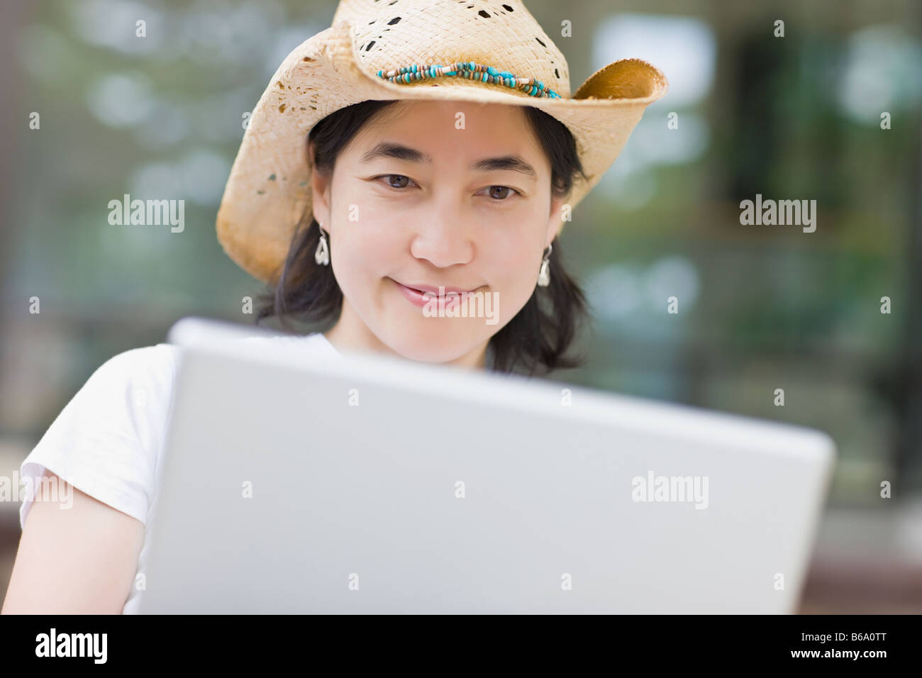Japanese woman typing on laptop wearing cowboy hat Stock Photo Alamy