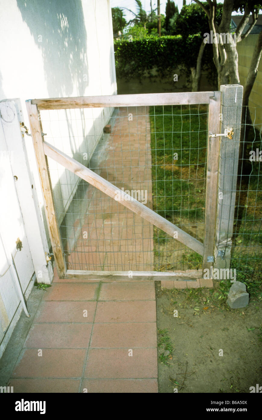 Wooden gate with metal screen mesh and diagonal support. Stock Photo