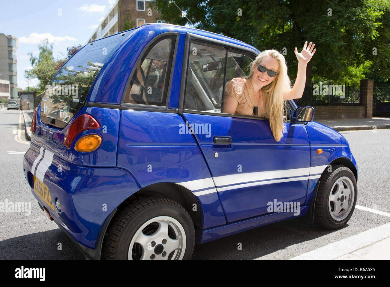 Young woman waving from electric car Stock Photo