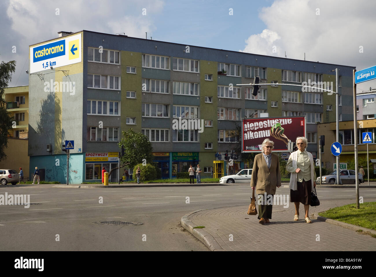 Women walking on street in town with concrete building and advertisements in background Slupsk Poland Stock Photo