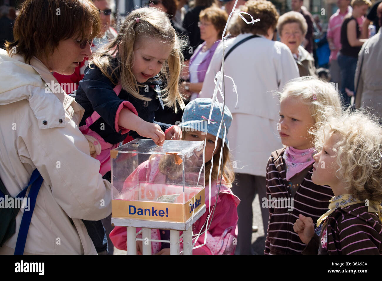 Children putting money into charity colleciton box Hamelin Germany Stock Photo
