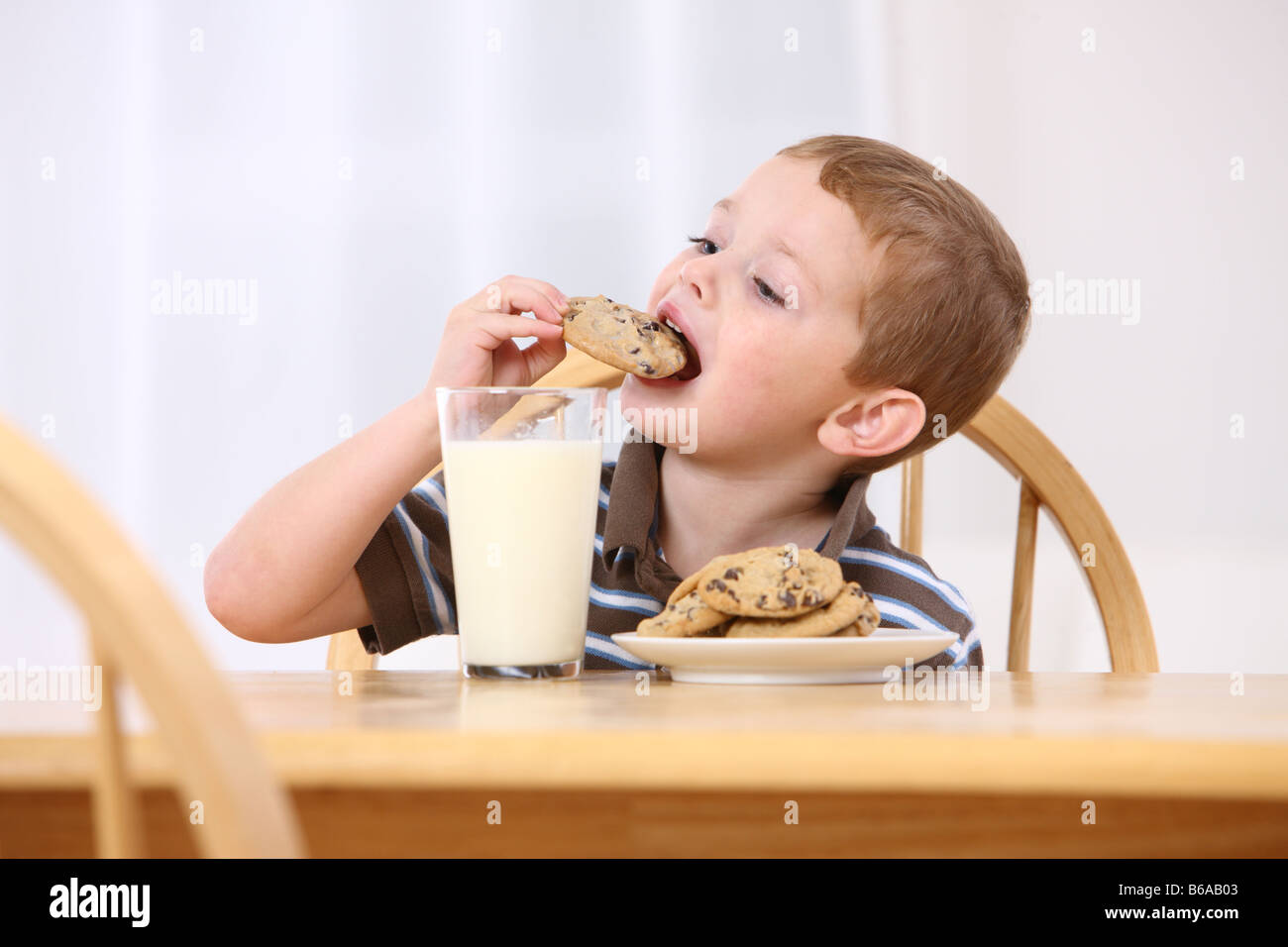 Young boy eating chocolate chip cookies and milk Stock Photo Alamy