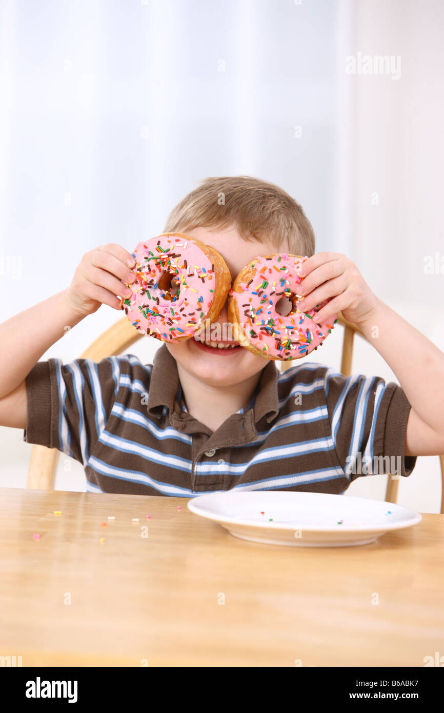 Young boy holding doughnuts over eyes Stock Photo